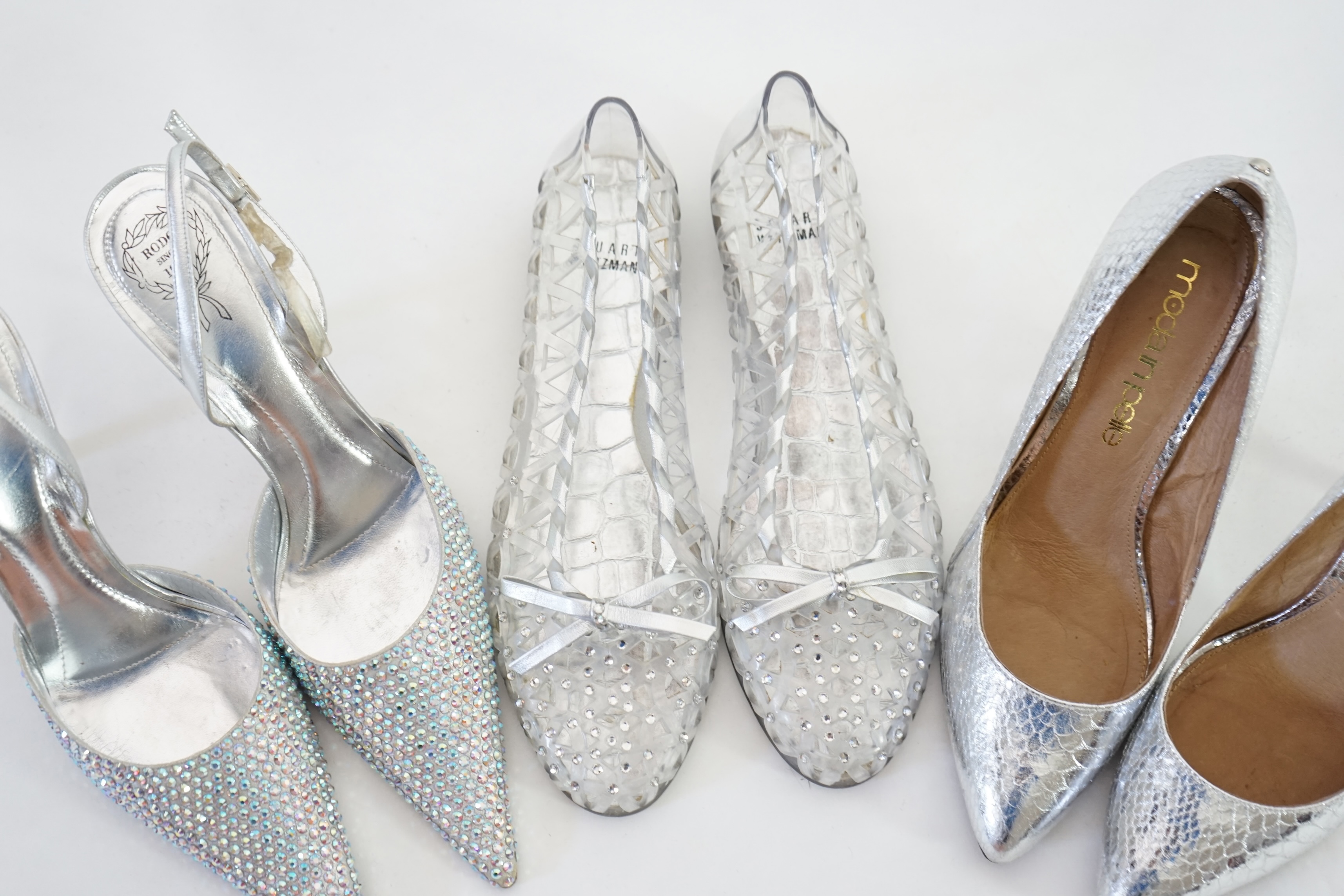 Three pairs of lady's silver shoes: Rodo silver diamonté sling back heels, Moda in Pelle silver snakeskin pattern heeled pumps and a pair of Stuart Weitzman clear jelly's with crystals. Size 38.5 (UK 4). Proceeds to Happ